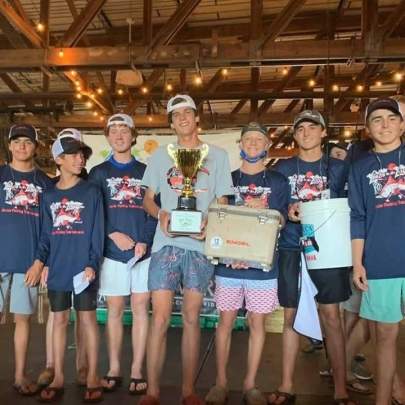 Boy holding a trophy on the stage with other boys 